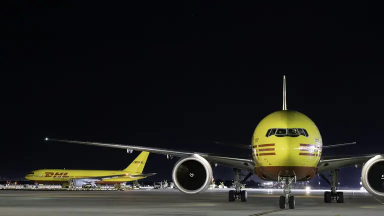Two Trade cargo planes parked on a runway at night.