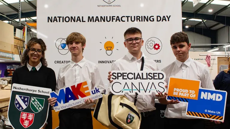 Four students pose with signs for Specialized Canvas and National Manufacturing Day.