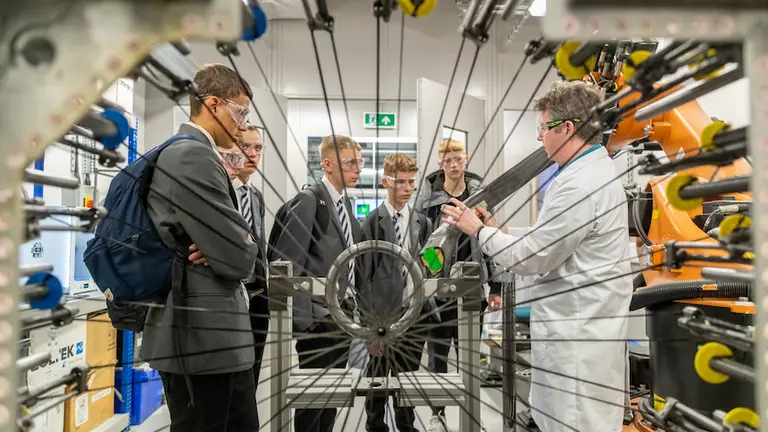 A group of people in lab coats and suits are standing in a factory.