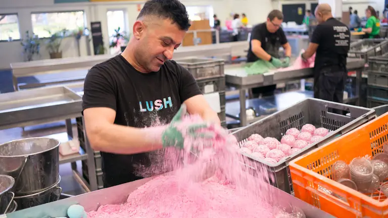 A man working during NMD at Lush pouring pink bubble bath.