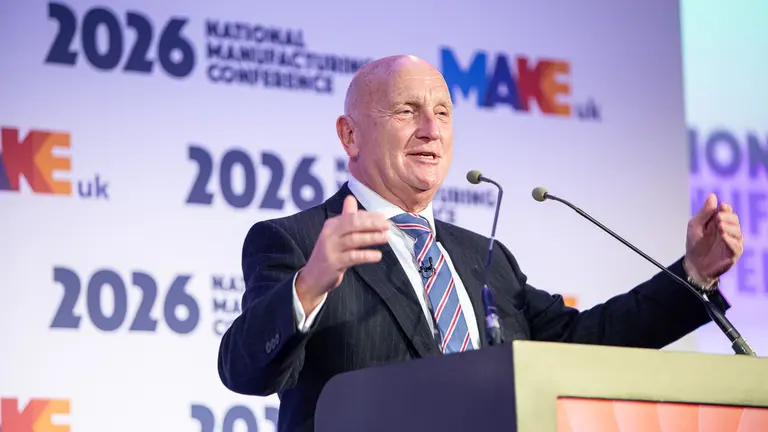Make UK speaking at a podium with "Make UK" and "2026" signs in the background.