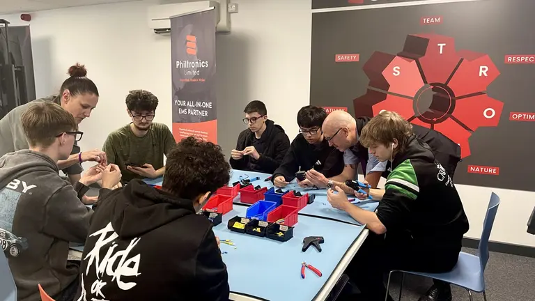 Students gathered around a table working on an electronic project for national manufacturing day 2025.