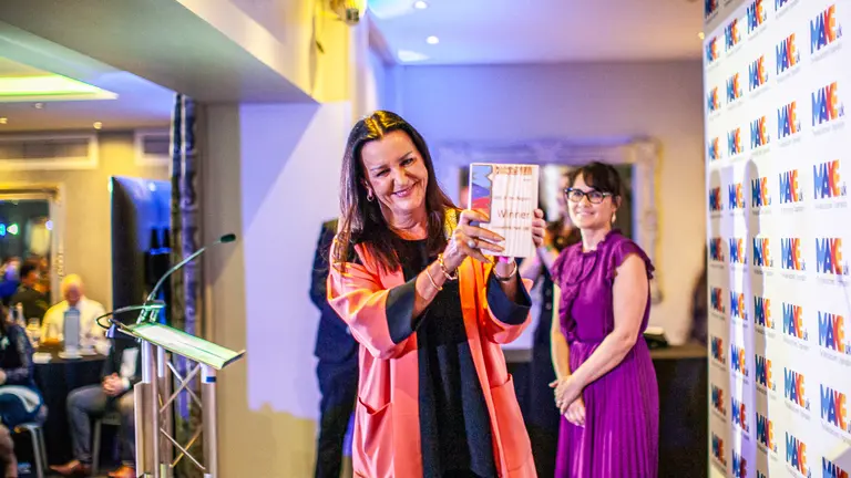 Woman holding a Make UK Award with a crowd in the background