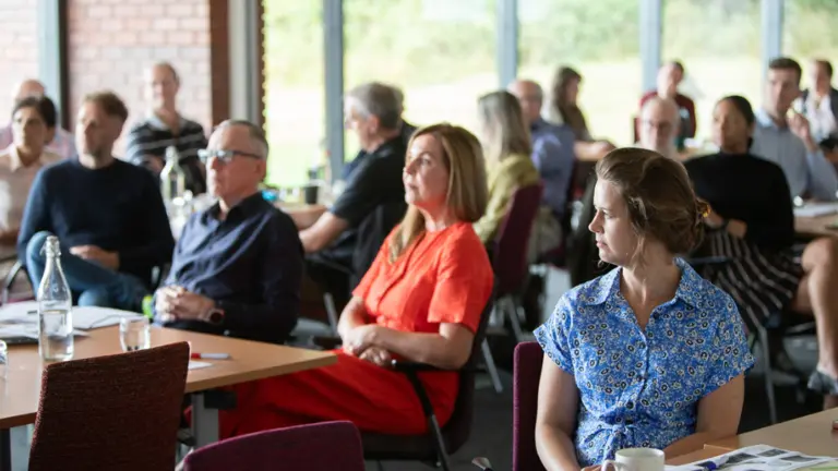Delegates sitting listening carefully to a presenter at an event