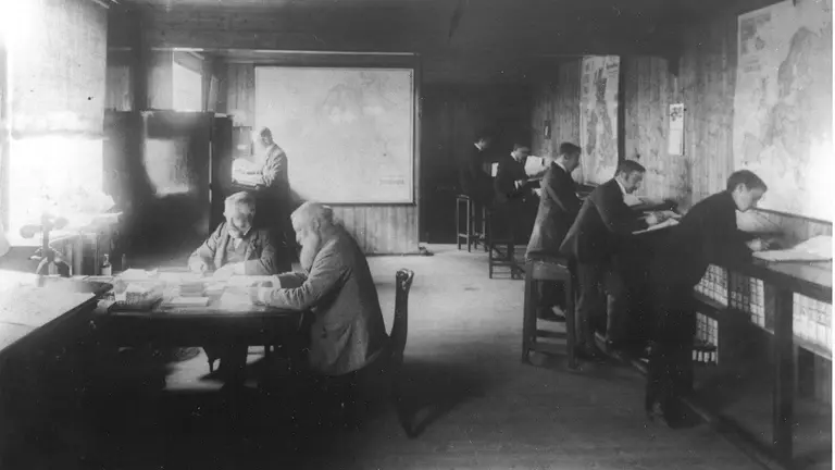 Black and white photo of men sitting at desks in a room at James Dawson.