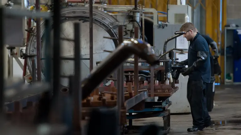 A man working in a factory wearing a protective arm sleeve.