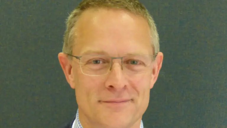 Man wearing glasses and in business attire smiling for the camera.