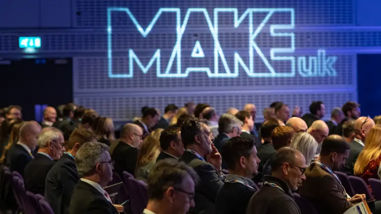 Audience at a conference with MAKEuk logo on a screen.