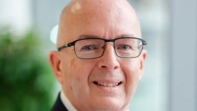 Man with glasses in a business suit, smiling at the camera.