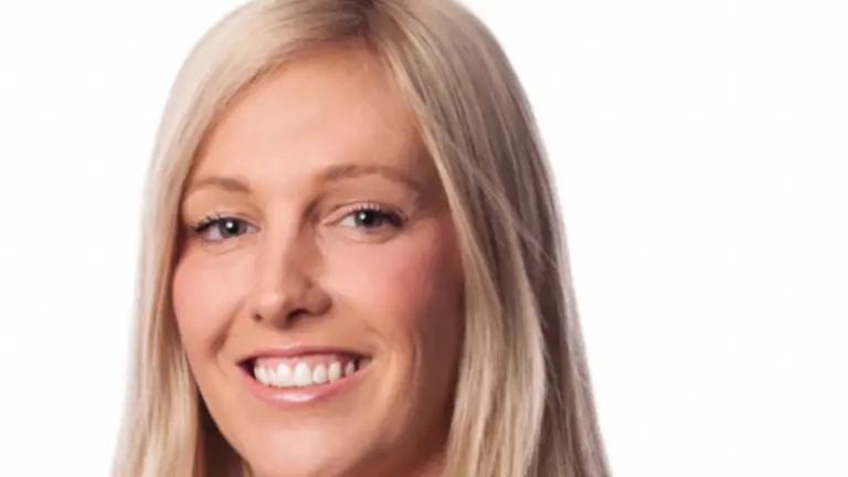 A woman in business attire smiles at the camera.