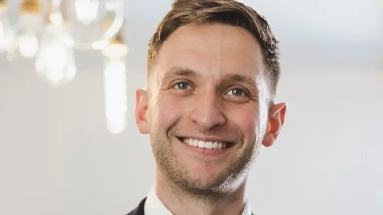 Man in suit and tie smiling for the camera.