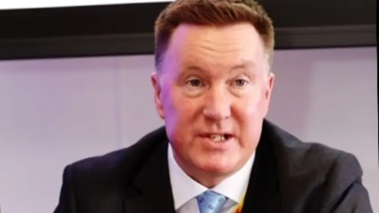 Man in a suit speaking into a microphone.