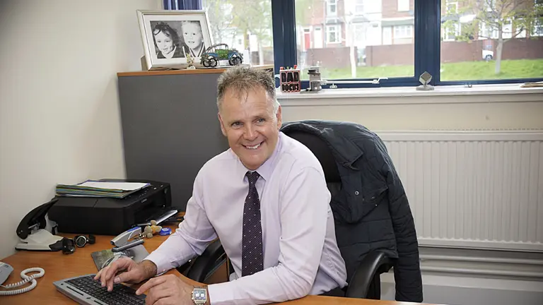 Man smiling at his desk.