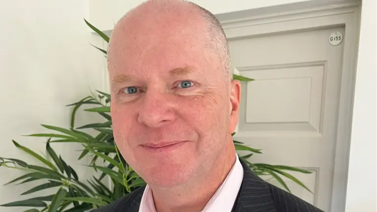 Man in business suit smiling in front of plant