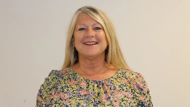 Woman in a floral blouse smiling at the camera