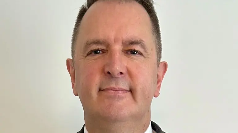 Man in suit and red tie smiling at camera.