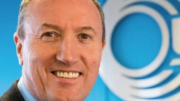 Man smiling against blue background with a logo