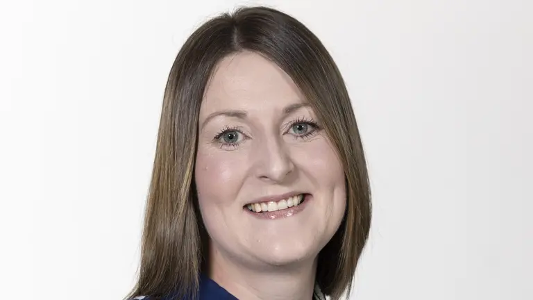 Woman wearing a blue dress, smiling at the camera.