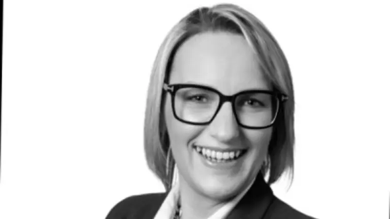 Smiling woman in business suit with glasses.