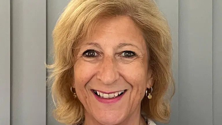 Woman smiling at camera wearing a white floral shirt.
