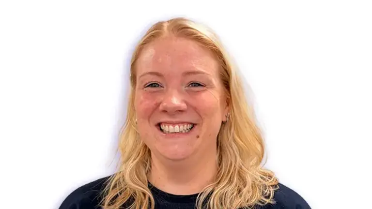 Smiling woman in navy blue shirt with a logo on the chest.