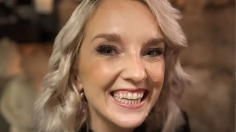 A smiling woman with short hair wearing a black top.