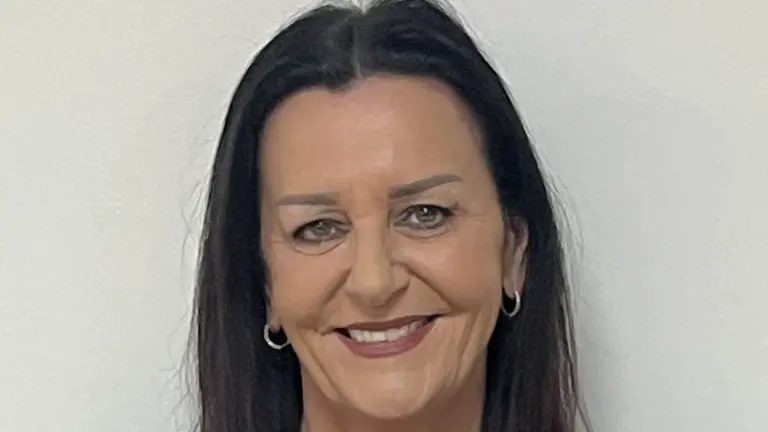 Woman wearing black and teal blouse, smiling.