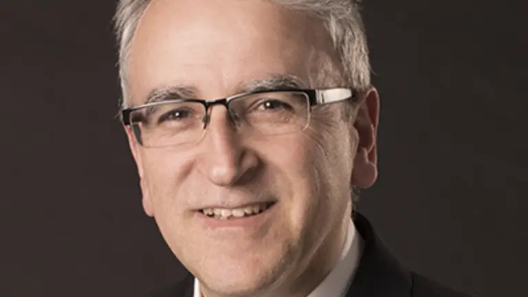 Man with glasses in business suit smiling.
