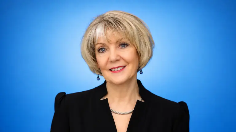 Smiling woman in black suit on a blue background.