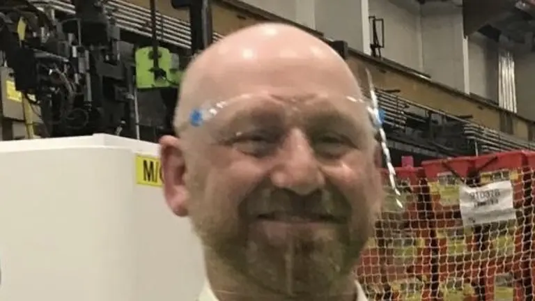 Man in high-visibility vest holding a black Henry vacuum cleaner.