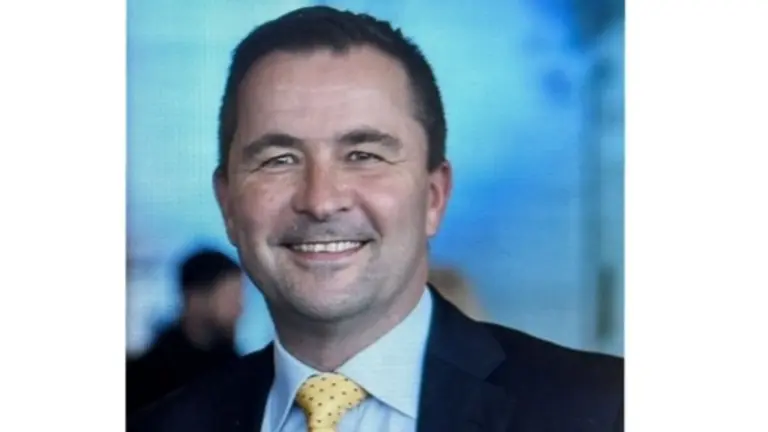 Businessman smiling in a suit and yellow tie.