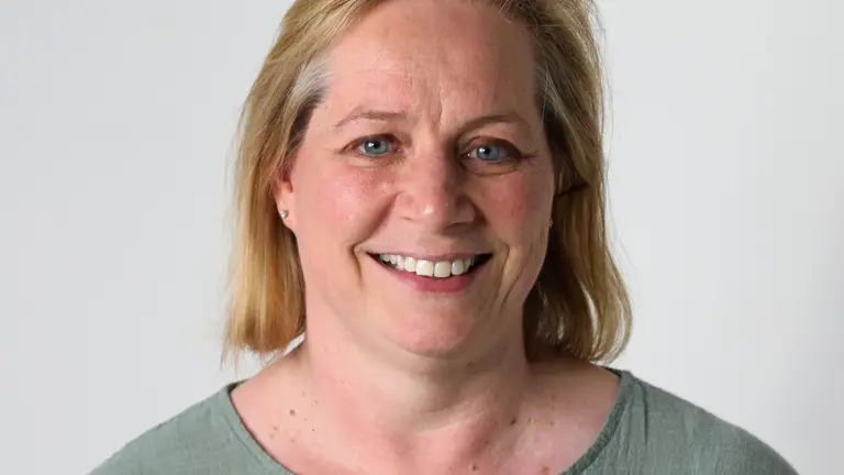 A smiling woman with blonde hair wearing a green top.
