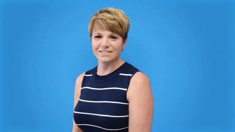 Woman with blonde hair in a black and white striped sleeveless top against a blue background.