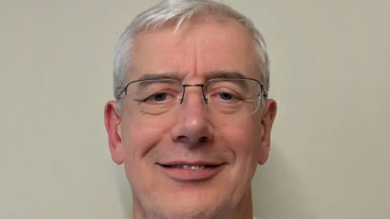 Man wearing glasses and white shirt, smiling for a photo