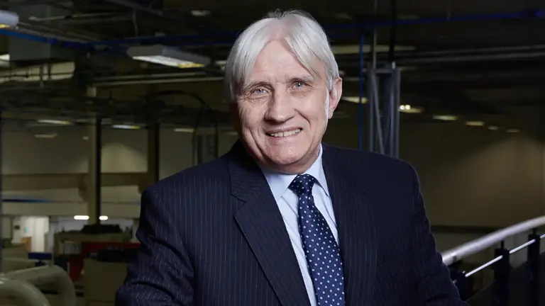 Older man in a suit and tie smiling at the camera.