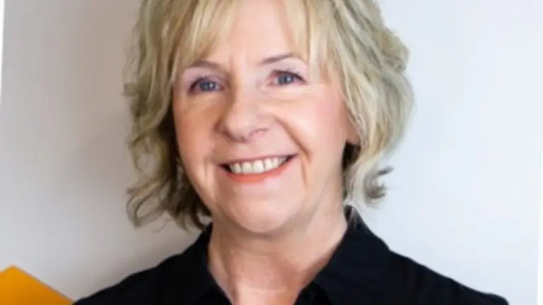 A smiling woman with short blonde hair in a black shirt.