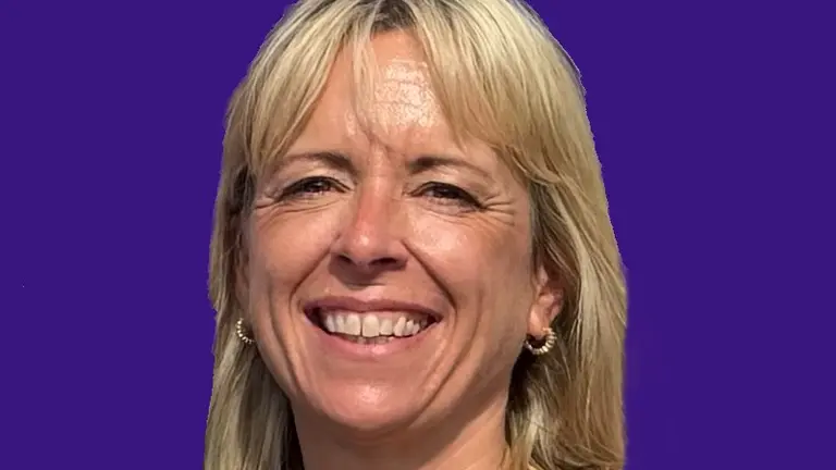 Woman with blonde hair and a zebra-print top smiling at the camera.