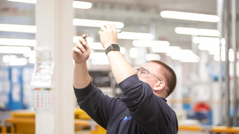 Apprentice in a factory with a tool in his hand