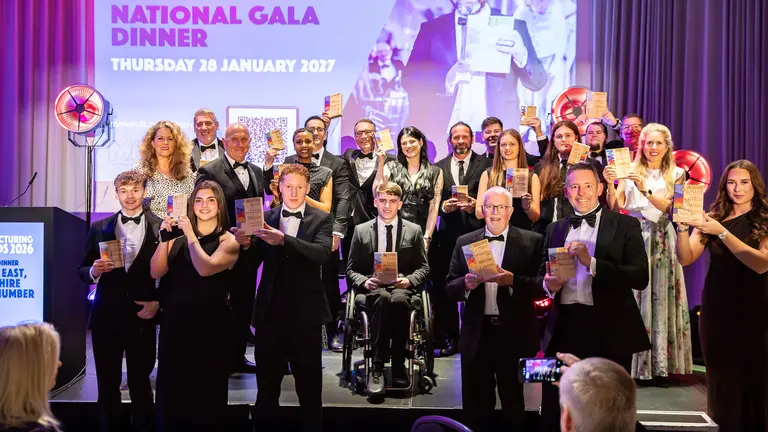 A group of people in suits pose with awards at a gala.