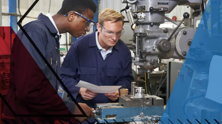 Young man using drilling machinery in a factory setting whilst another looks on. Make UK branded