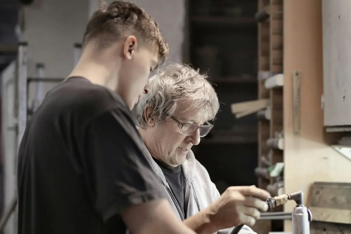 Image of Apprentice helping teacher in a workshop