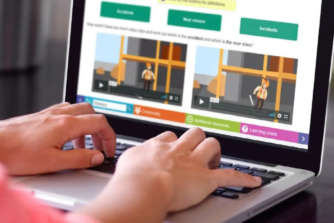 Person typing on laptop with video about safety on screen.