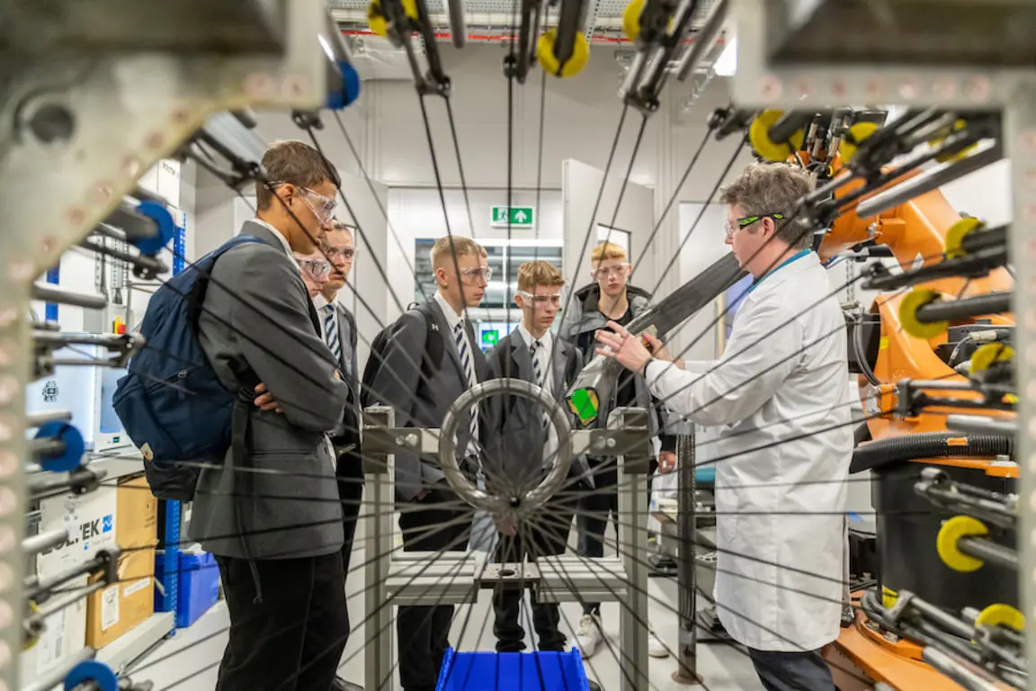 A group of people in lab coats and suits are standing in a factory.