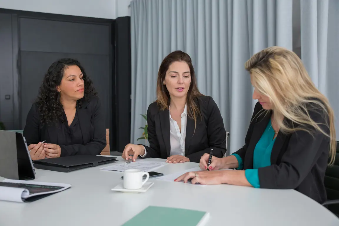 women in black blazers sitting down while having a discussion