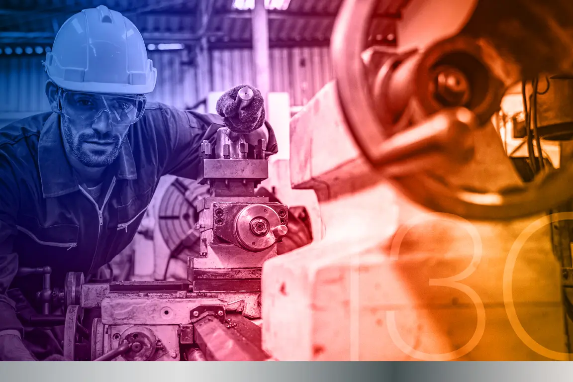 Man wearing hard hat working on industrial machine in factory.