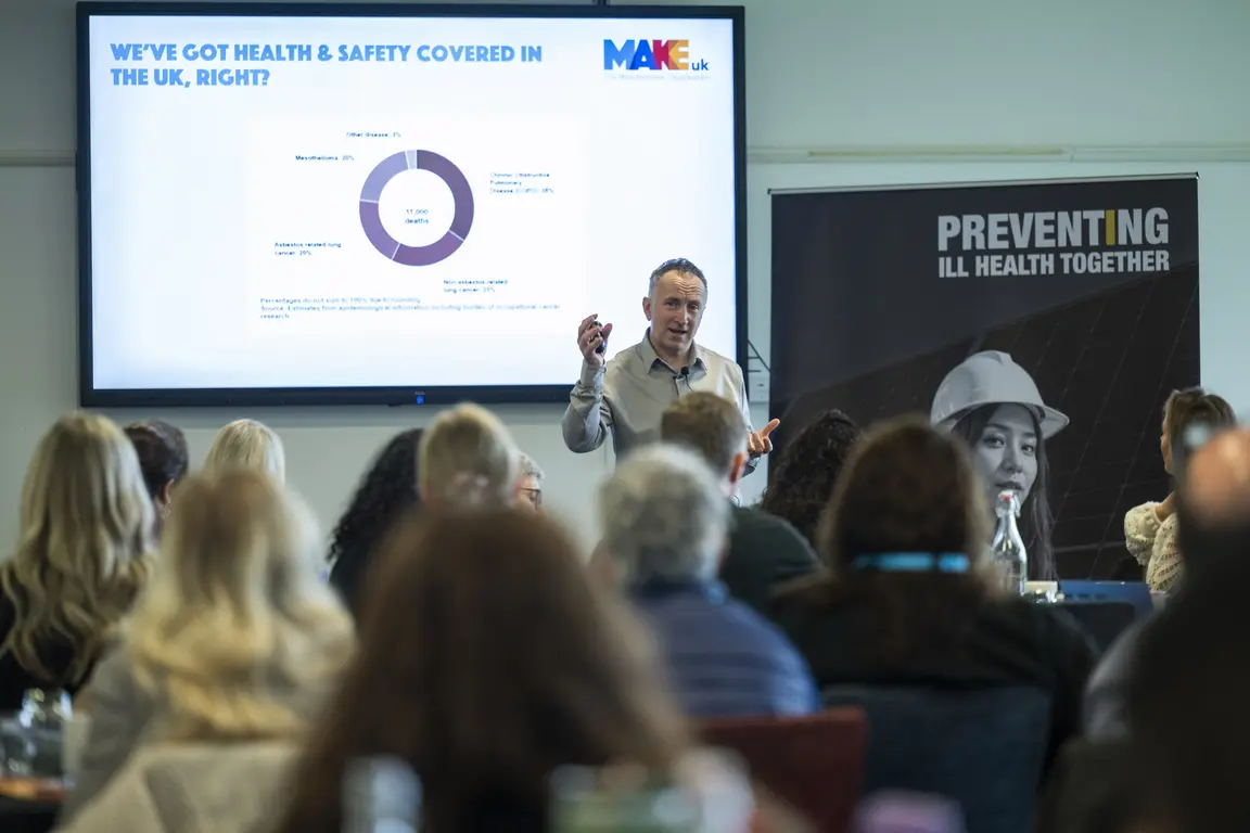 A man giving a EHS presentation to an audience in a room.