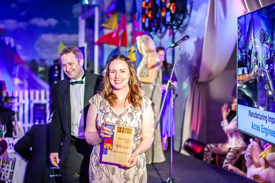 Woman with a award smiling at the make uk awards gala event