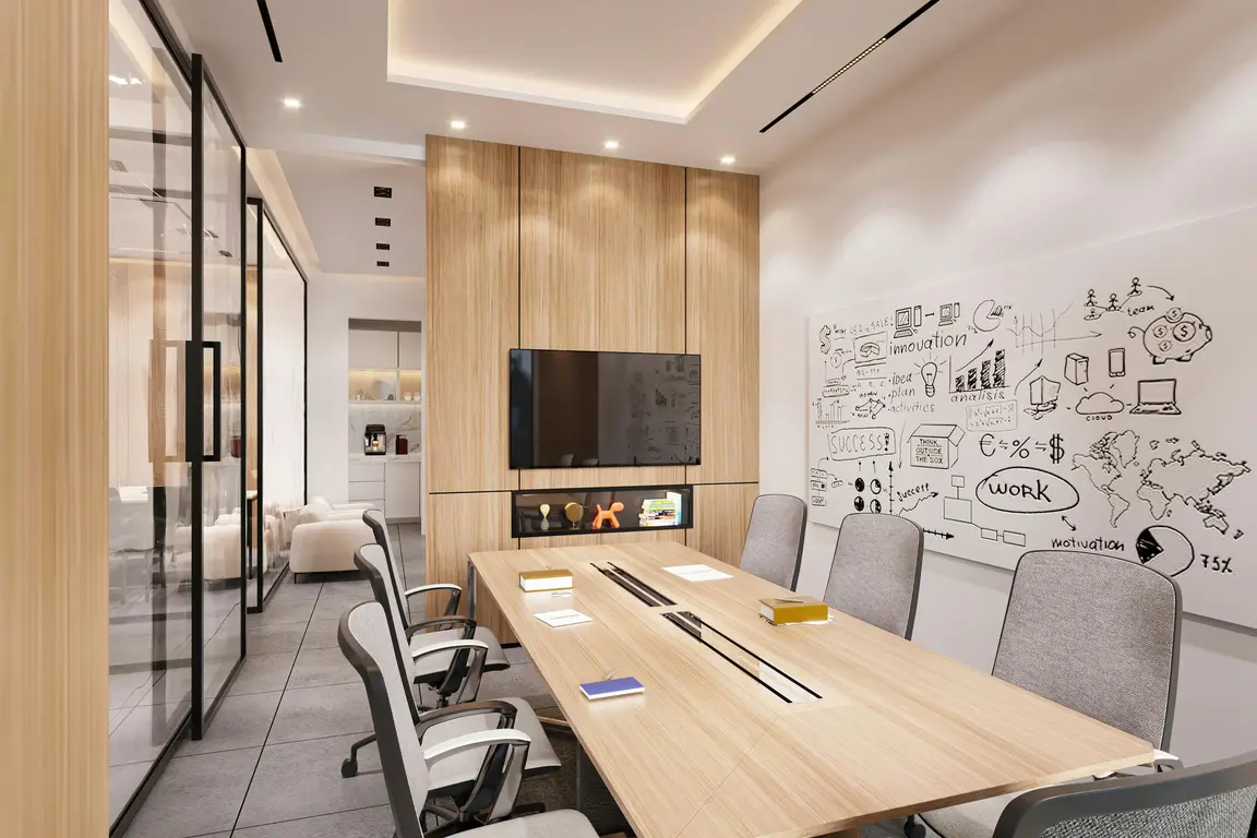 Empty conference room with large wooden table, chairs, whiteboard with drawings, and a flat screen TV.