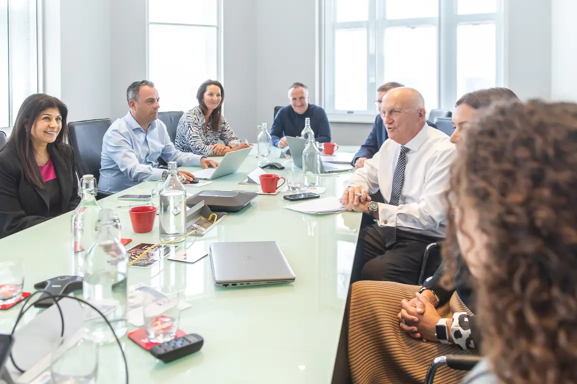 Image of board members in discussion around board table
