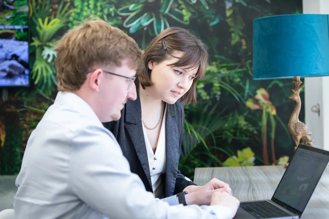 Image of two colleagues in discussion whilst looking at a laptop